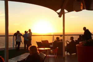 Personas disfrutando del atardecer en la cubierta de un crucero