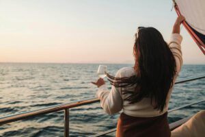 Mujer disfrutando de un crucero mirando el horizonte con una copa en la mano